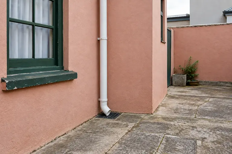Illustration of a downpipe discharging towards a drainage inlet