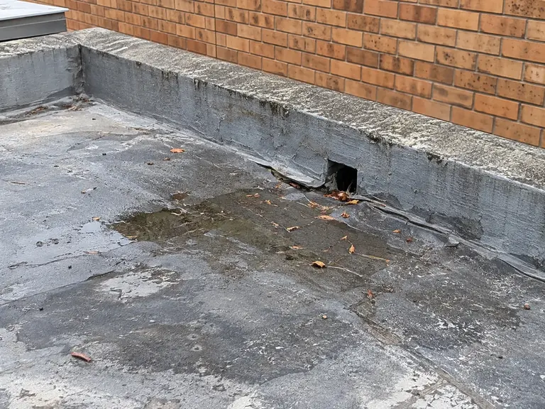 Illustration of a worn flat-roof surface and drainage outlet